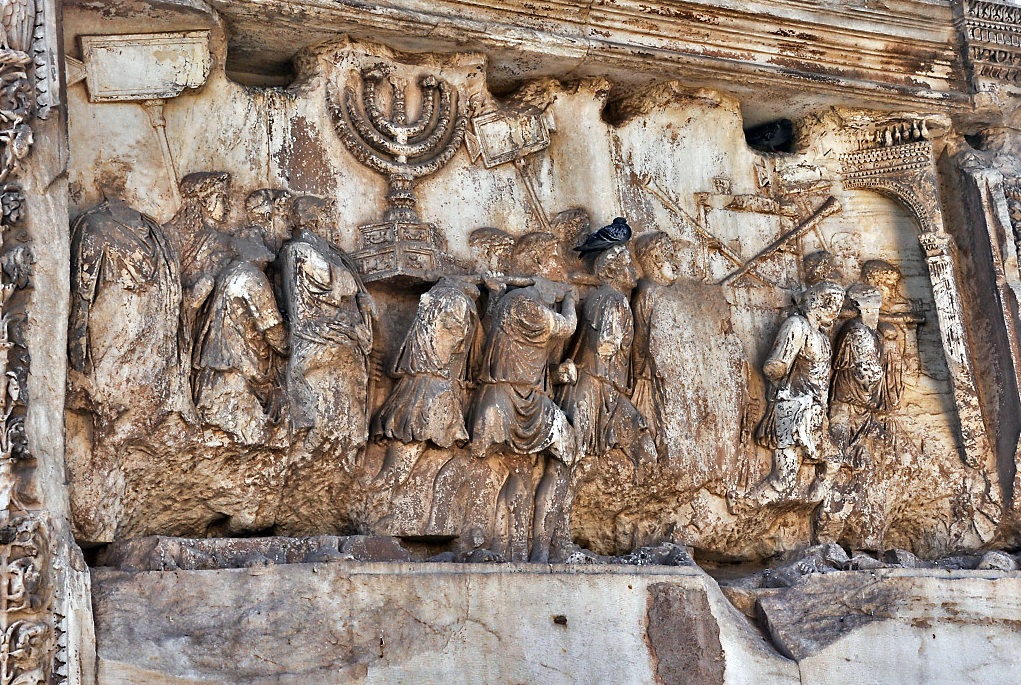 上图：提多凯旋门的浮雕，描绘罗马士兵扛着从耶路撒冷圣殿掳来的金灯台、长号和陈设饼桌。多米田皇帝在他哥哥提多皇帝去世后不久，建了一座大理石单拱凯旋门，以纪念提多率军于主70年摧毁耶路撒冷，平息了主后66年开始的犹太人起义。直到今天，许多犹太人拒绝从拱门下经过。1948年以色列复国时，大批人群从罗马犹太社区沿着与古罗马凯旋式相反的方向通过提图斯凯旋门。