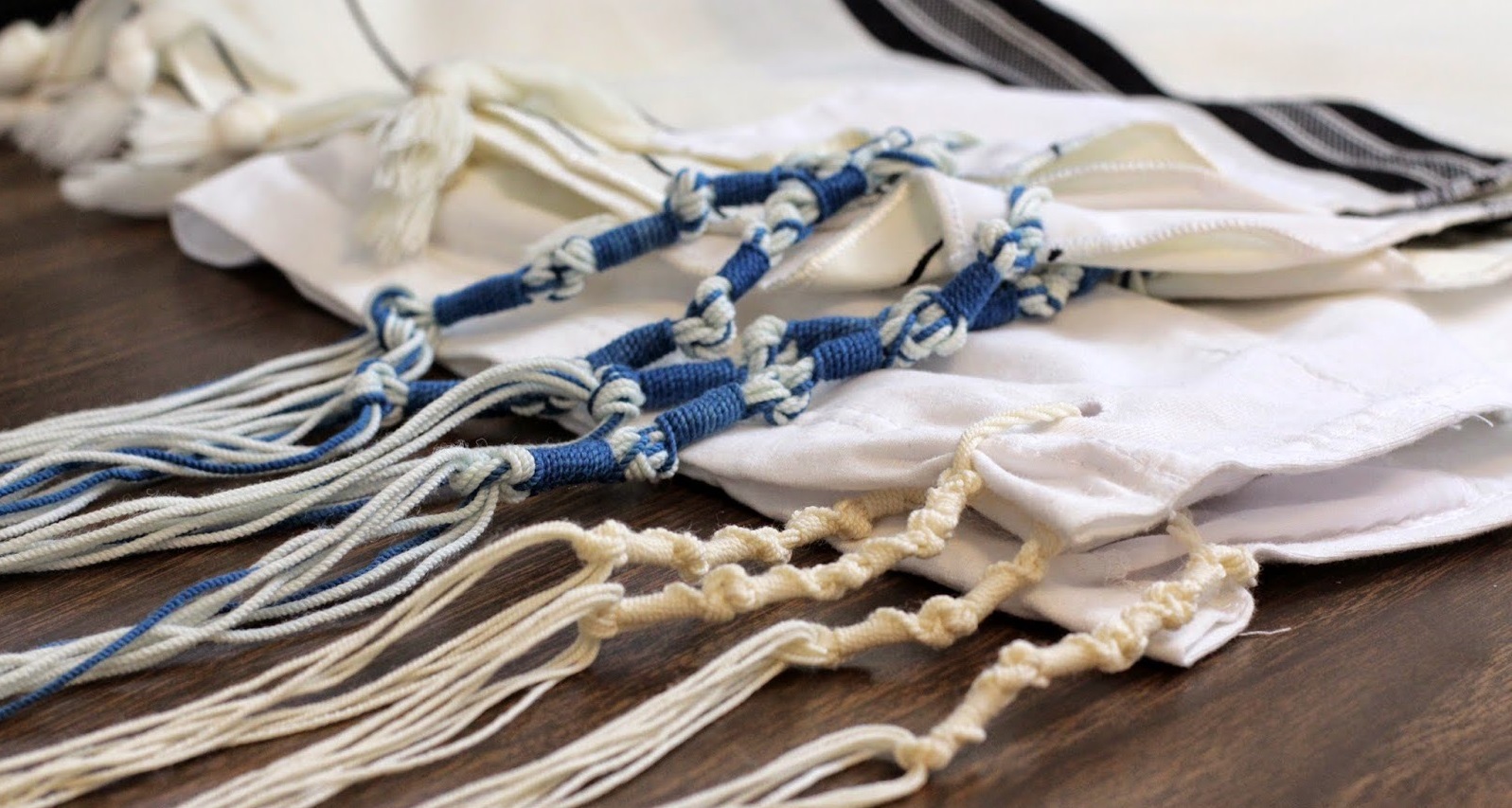 上图:犹太人根据民十五37-40和申二十二12,在衣服下摆佩带的䍁子,提醒自己「记念遵行耶和华一切的命令,不随从自己的心意、眼目行邪淫」。「䍁子」的希伯来文「Tzitzit/?????」数值是400+10+90+10+90=600。每个䍁子都由5个结和8根线组成,5个结代表摩西五经,8根线代表完全。600+5+8=613,象征摩西律法中的613条律例和典章。东欧阿什肯纳兹犹太人(Ashkenazi)的䍁子5个结之间的圈数是7+8+11+13=13*3,是「神是独一」(申六4)的希伯来文数值。西班牙塞法廸犹太人(Sephardi)的䍁子5个结之间的圈数是10+5+6+5=13*2,是「耶和华」的希伯来文数值。